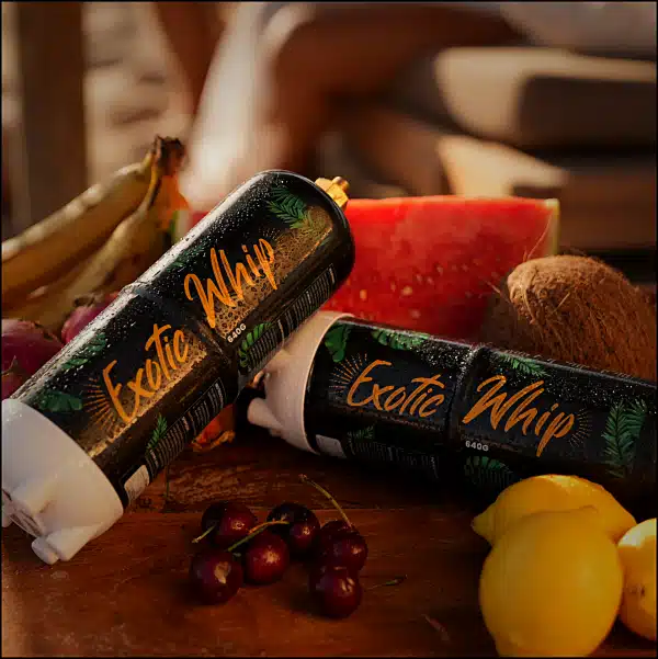 Two Exotic Whip Cream canisters on the beach with fruit watermelon