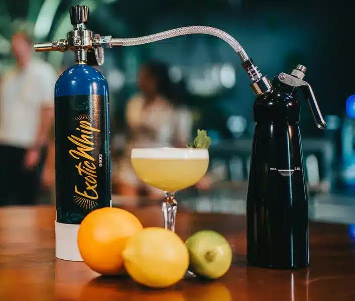 a whip cream dispenser being filled with nitrous oxide by a cream charger